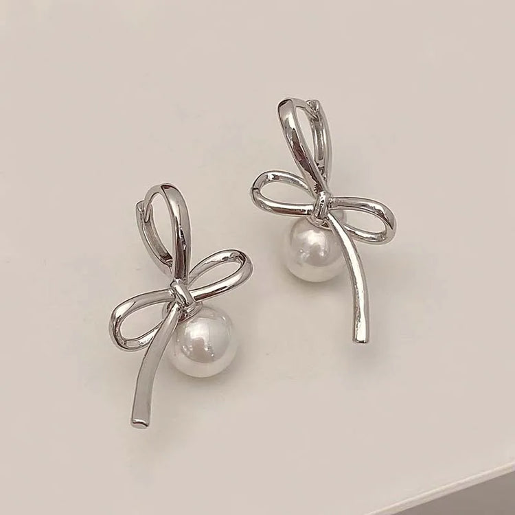 Silver Pearl Whim Bow Earrings displayed on white surface