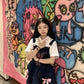 Pocket Full of Love Overall Dress styled over a white collared shirt against colorful artwork