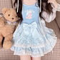 Model sitting beside a teddy bear while wearing the blue Polka Dot Sweetie Tiered Skirt with lace trim and removable oversized bow pin.