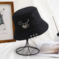 The Rebel Charm Bucket Hat displayed on a stand showing the full shape and charm details in a styled setting.
