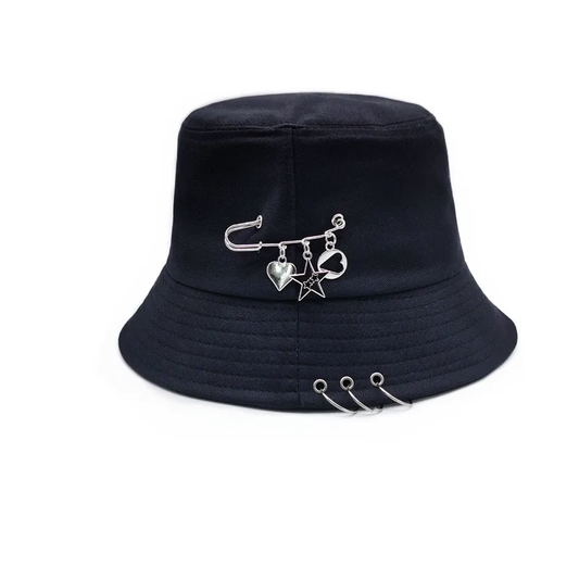 The Rebel Charm Bucket Hat in black featuring safety pin and dangling charm details on a structured bucket silhouette.