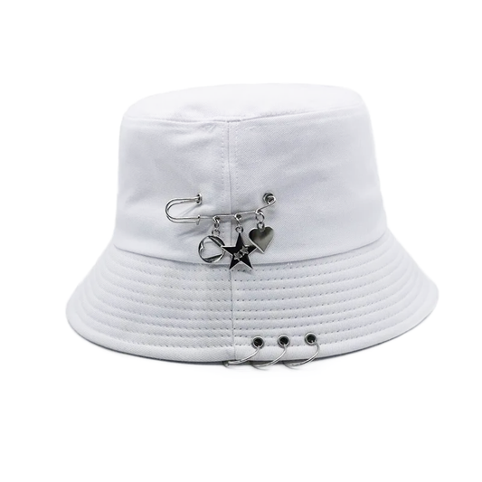 The Rebel Charm Bucket Hat in white with safety pin and charm accents creating a soft yet edgy aesthetic.
