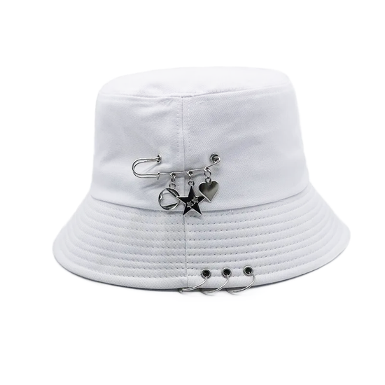 The Rebel Charm Bucket Hat in white with safety pin and charm accents creating a soft yet edgy aesthetic.