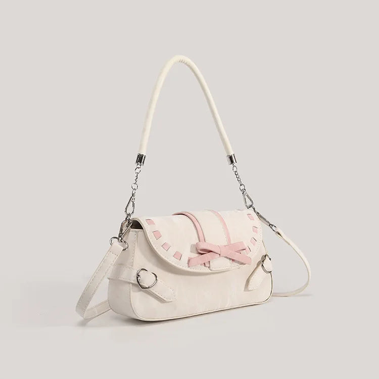 Angled front view of the Ribbon Romance Shoulder Bag, highlighting the detachable shoulder strap, heart-shaped buckle accents, and structured satchel silhouette.