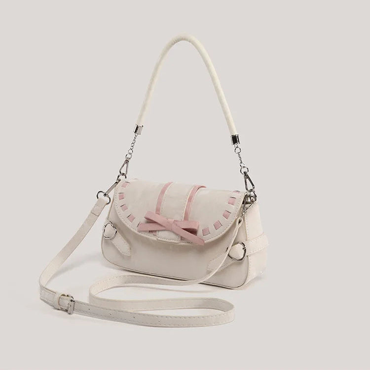 Front view of the cream Ribbon Romance Shoulder Bag with the detachable shoulder strap displayed, highlighting the statement ribbon bow, interwoven ribbon detailing, heart-shaped buckle accents, and soft velvety finish.