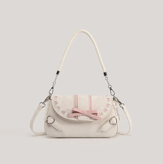 Front view of the cream Ribbon Romance Shoulder Bag, featuring a statement ribbon bow, interwoven ribbon detailing, heart-shaped buckle accents, top handle, and detachable shoulder strap.