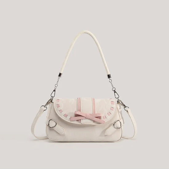 Front view of the cream Ribbon Romance Shoulder Bag, featuring a statement ribbon bow, interwoven ribbon detailing, heart-shaped buckle accents, top handle, and detachable shoulder strap.