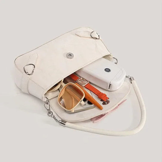 The Ribbon Romance Shoulder Bag in cream opened to display the polyester-lined interior, hidden magnetic snap closure, and interior zip pocket.