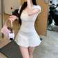 Model wearing the white Ruffled Romance Top with a white pleated skirt and pink handbag, shown from a side angle.