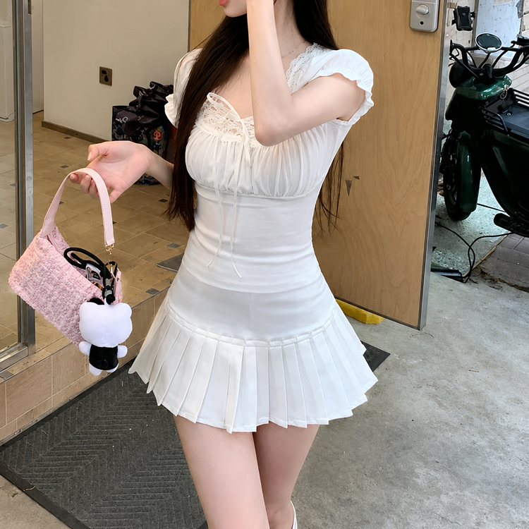 Model wearing the white Ruffled Romance Top with a white pleated skirt and pink handbag, shown from a side angle.