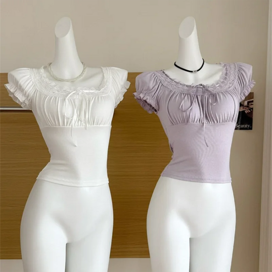 White and soft purple Ruffled Romance Tops displayed on mannequins, showing the fitted shape, lace-trimmed neckline, ribbon ties, and ruffled sleeves.