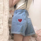 Scarlet Sweetheart High-Rise Shorts back pocket closeup, showcasing light blue denim, high waist, red heart embroidery, and lace trim pocket