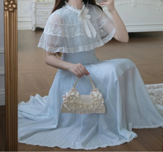 Model squatting in the Seraphina Lace Midi Dress showing the flowing blue skirt and lace capelet.