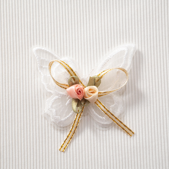 Close-up of lace butterfly appliqué with floral accent and bow on the Serene Butterfly Crop Top