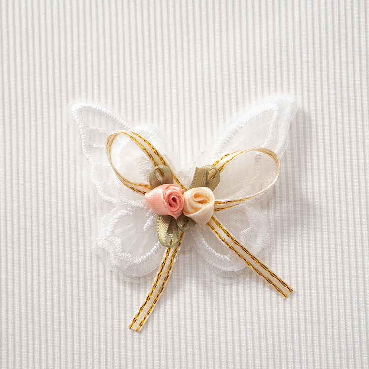 Close-up of lace butterfly appliqué with floral accent and bow on the Serene Butterfly Crop Top