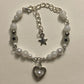 Close-up of the white Set Apart Star Bracelet with pearl heart charm and black star beads on a light background.
