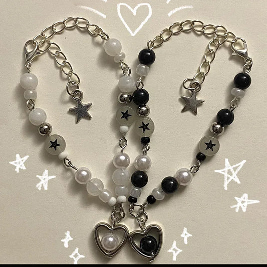 Set of the Set Apart Star Bracelets, black and white heart charm bracelets with star beads, laid out in a heart shape on a cream background with hand-drawn stars and hearts.