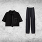 Black short-sleeve cropped button-up shirt from the Shadow Chain Utility Set featuring a matching black tie, removable safety pin with chain, and adjustable drawstring waist, paired with black utility pants featuring a detachable chain and drawstring hems.