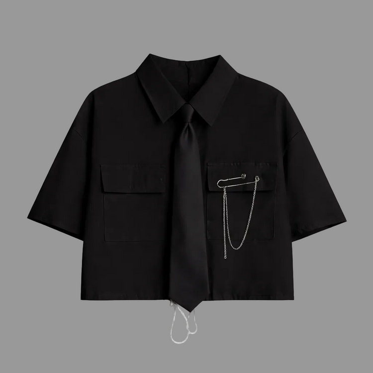 Black short-sleeve cropped button-up shirt from the Shadow Chain Utility Set featuring a matching black tie, removable safety pin with chain, and adjustable drawstring waist.