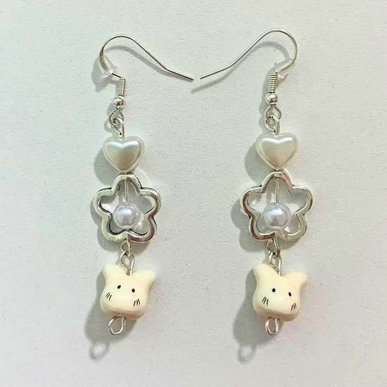 Flat lay of the Somebunny to Love Earrings on a neutral background, showcasing the pearl heart, pearl flower, and bunny charms