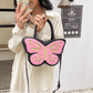 Sparkling Butterfly Handbag in black and pink being held by a model in front of a mirror