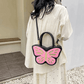 Sparkling Butterfly Handbag in black and pink being worn behind a model's back