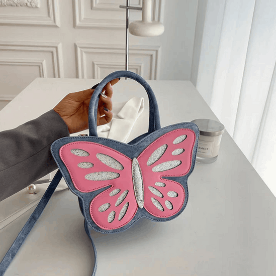 Model holding blue and pink Sparkling Butterfly Handbag up on a table