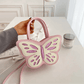 Model holding the Sparkling Butterfly Handbag in pink and white on a table