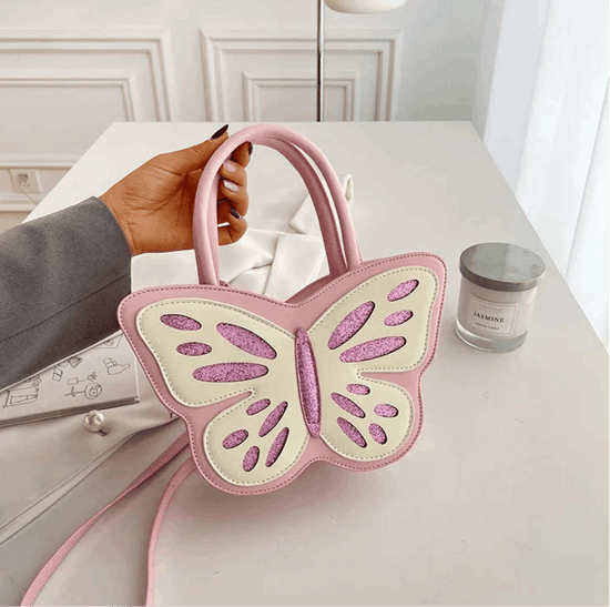 Model holding the Sparkling Butterfly Handbag in pink and white on a table