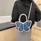 Model wearing Sparkling Butterfly Handbag in white and blue with crossbody strap behind their back