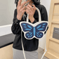 Model holding Sparkling Butterfly Handbag in white and blue in front of their body in a mirror