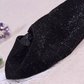 Folded pair of the Starlight Shimmer Tights in black with silver shimmer displayed on a white faux-fur surface.