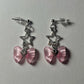 Starlit Dreams Bow Earrings with pink heart drops, silver bows, and star accents displayed on a neutral backdrop.