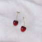 Dark red, small Sweet Cherry Earrings displayed on a white gauze-like background