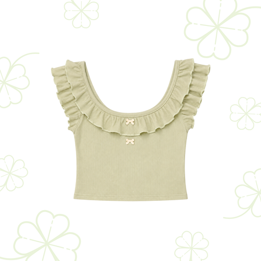 Sweet Clover Ruffle Top in light green with a ruffled scoop neckline and two small bow accents on a clover-patterned background.