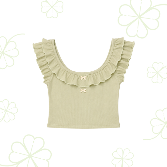 Sweet Clover Ruffle Top in light green with a ruffled scoop neckline and two small bow accents on a clover-patterned background.