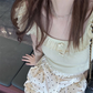Close overhead view of the Sweet Clover Ruffle Top showing its ribbed texture, ruffled scoop neckline, and small bow accents.