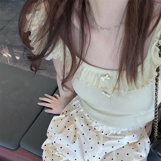 Close overhead view of the Sweet Clover Ruffle Top showing its ribbed texture, ruffled scoop neckline, and small bow accents.
