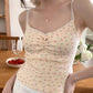 Side angle of apricot Sweet Flower Crop Top with red floral details worn by model indoors.