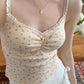 Close-up of model wearing apricot Sweet Flower Crop Top with pink floral print and lace straps.