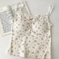 Flatlay of cream Sweet Flower Crop Top with multicolor mini floral print and hot pink center flower.
