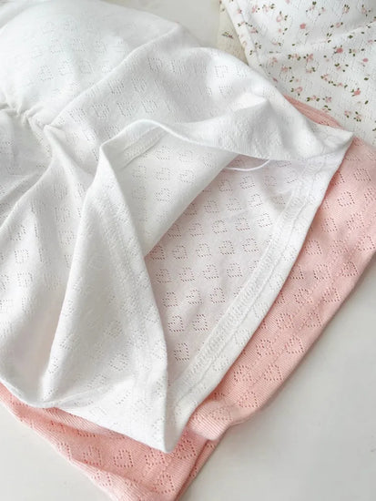 Flatlay of Sweet Flower Crop Tops in white and pink heart knit designs with soft texture.