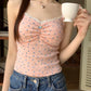 Model wearing pink Sweet Flower Crop Top with blue floral print and jeans, holding a teacup.