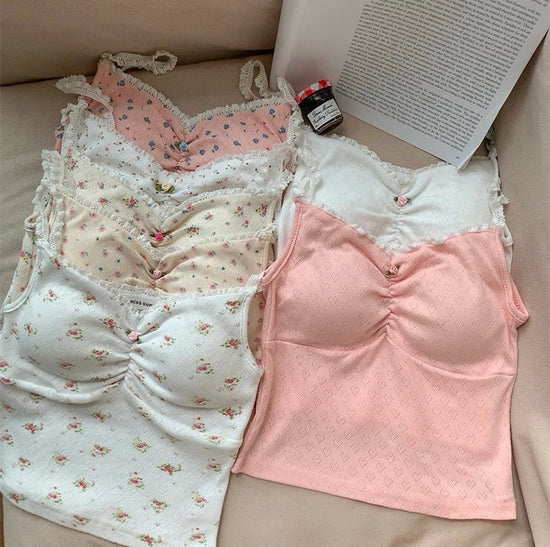 Flatlay of multiple Sweet Flower Crop Tops in floral, heart, and pastel styles arranged in a soft pastel set.