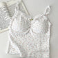 Flatlay of Sweet Flower Crop Top in white with tiny pink floral pattern, laid next to an open book.