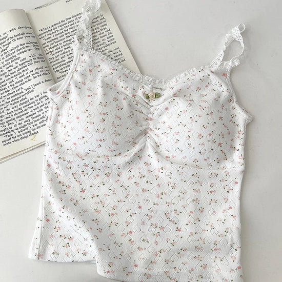 Flatlay of Sweet Flower Crop Top in white with tiny pink floral pattern, laid next to an open book.