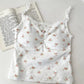 White/red floral Sweet Flower Crop Top laid flat next to an open book, featuring lace trim and ruched bust.