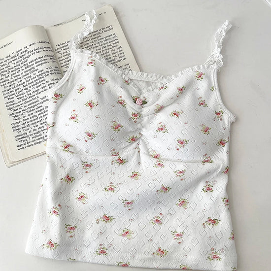 White/red floral Sweet Flower Crop Top laid flat next to an open book, featuring lace trim and ruched bust.