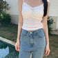 Model outdoors wearing white Sweet Flower Crop Top with jeans, showcasing the top's lace trim and ruched bust.