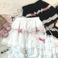 Close-up of the white/pink and black/pink Sweet Love Lace Bow Skort color options displayed next to matching tops.